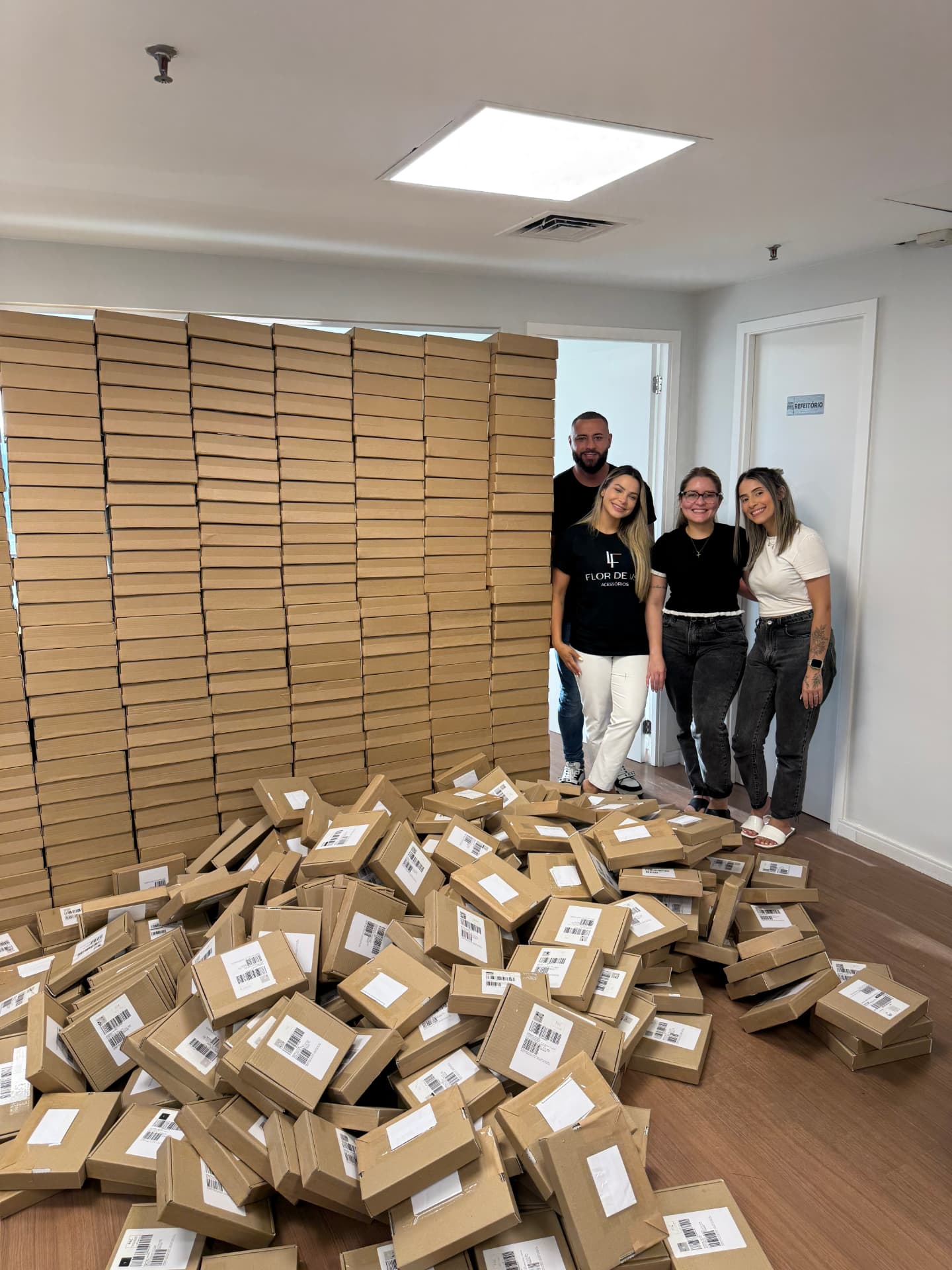 Eu e minha equipe ao lado de uma parede de pedidos embalados