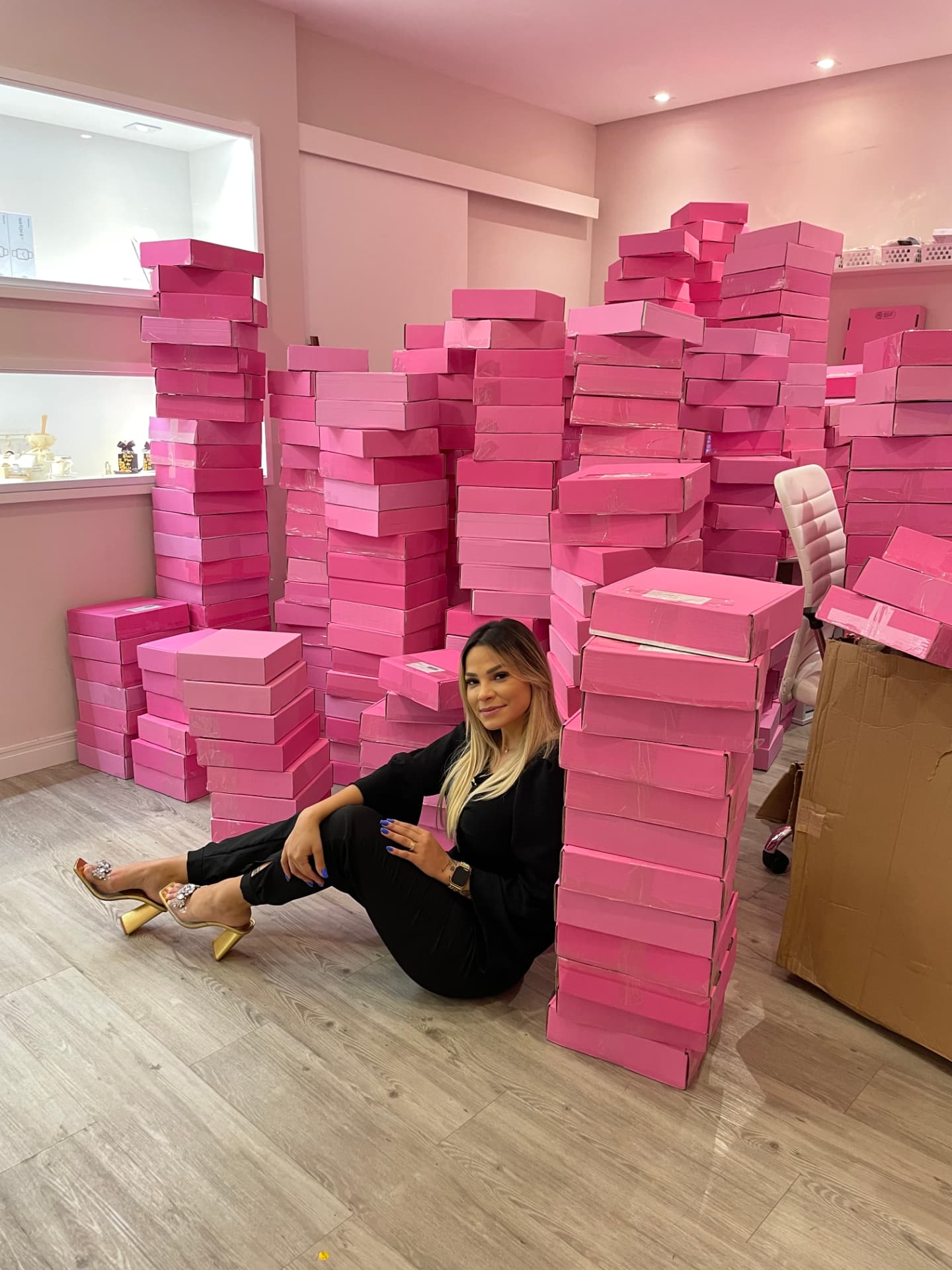 Eu sentada entre pilhas de caixas rosa de pedidos